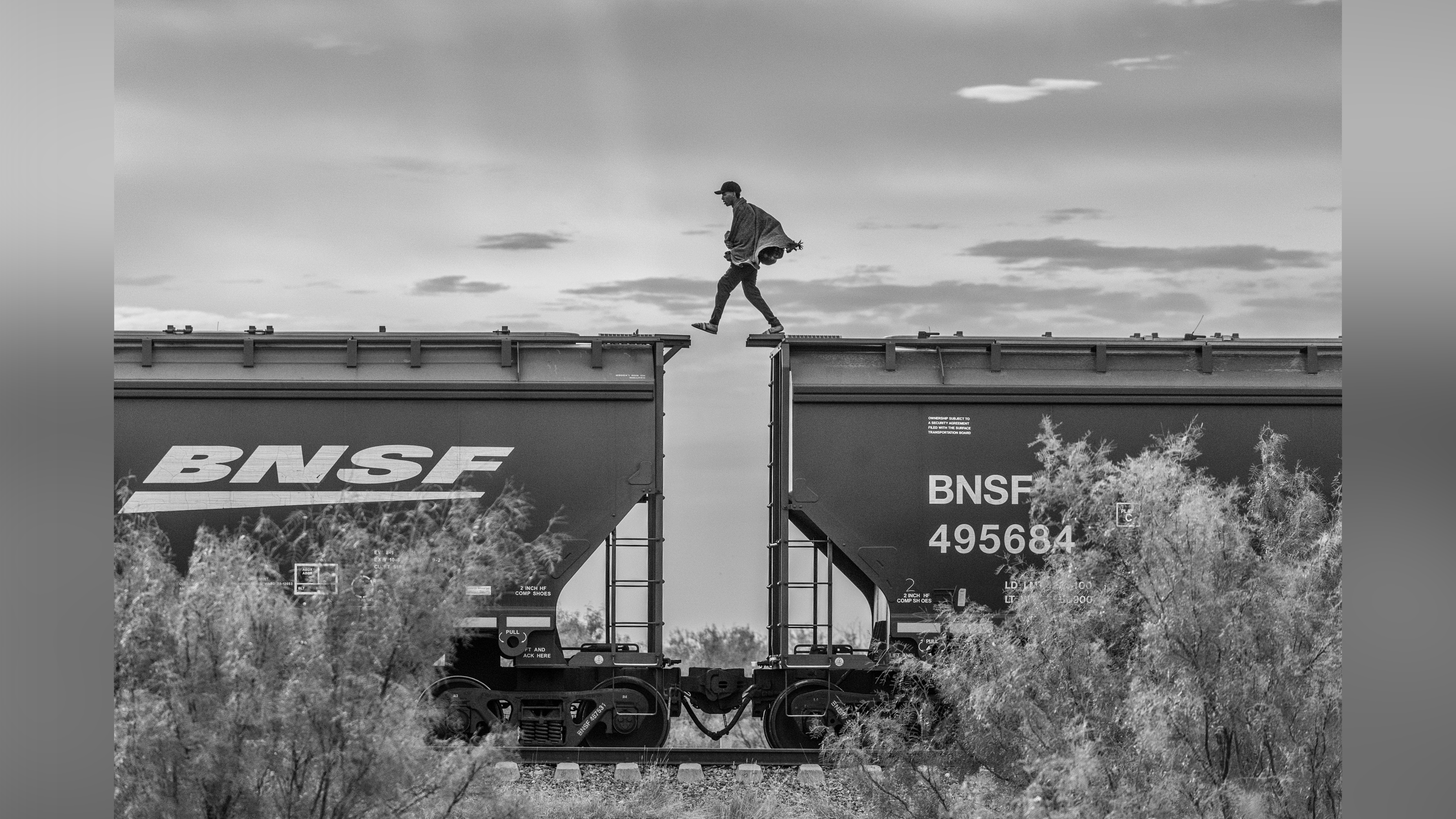 A migrant walks on top of a parked freight train known as “The Beast” on the outskirts of Piedras Negras, Mexico 2023.From the series “The Two Walls”