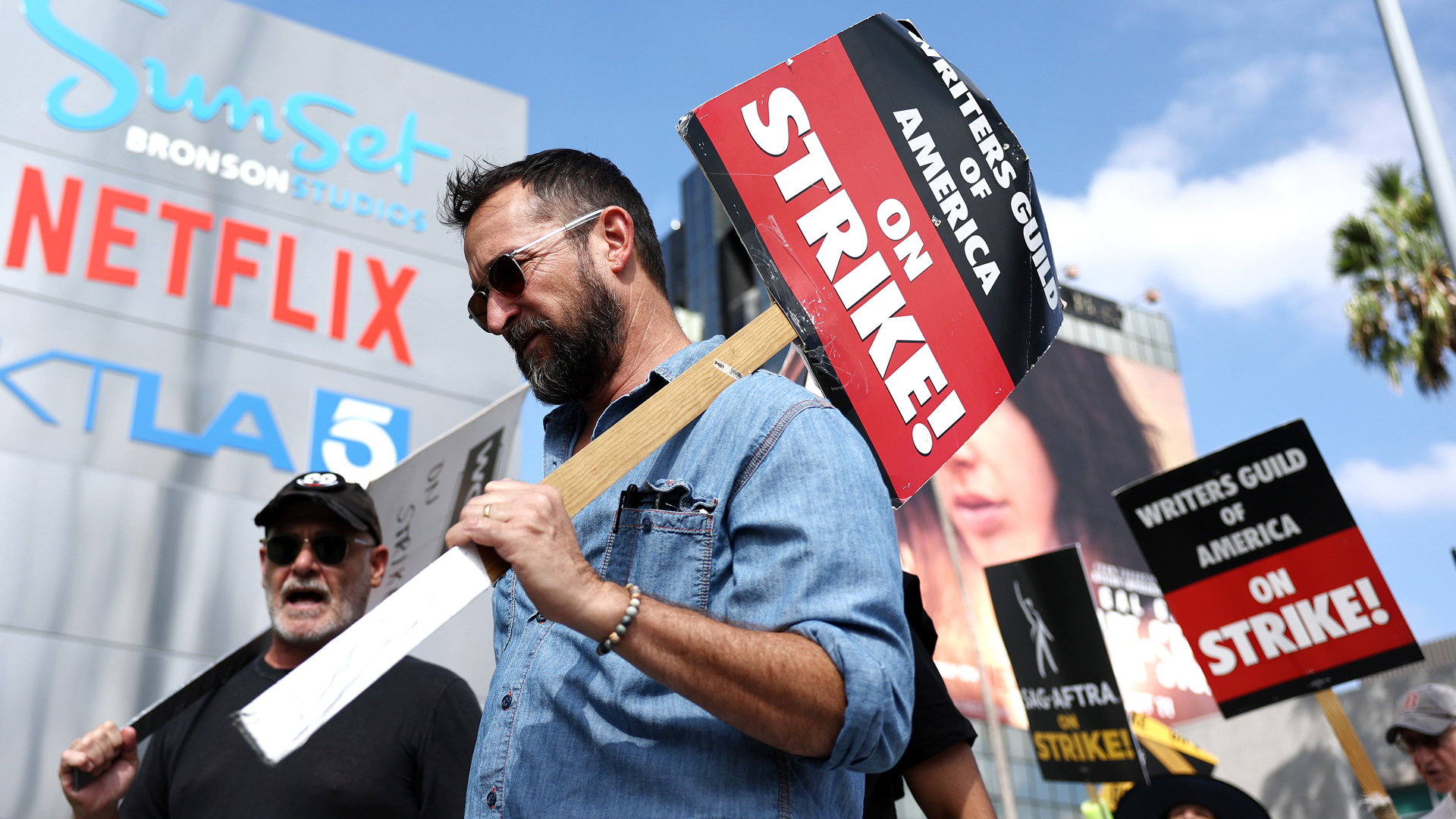A group of writers picket outside Netflix's LA-based studio with placards and other signs