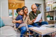 Worried parents looking at bills while cuddling child