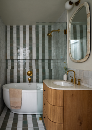 a white and green tiled wet room with a freestanding tub