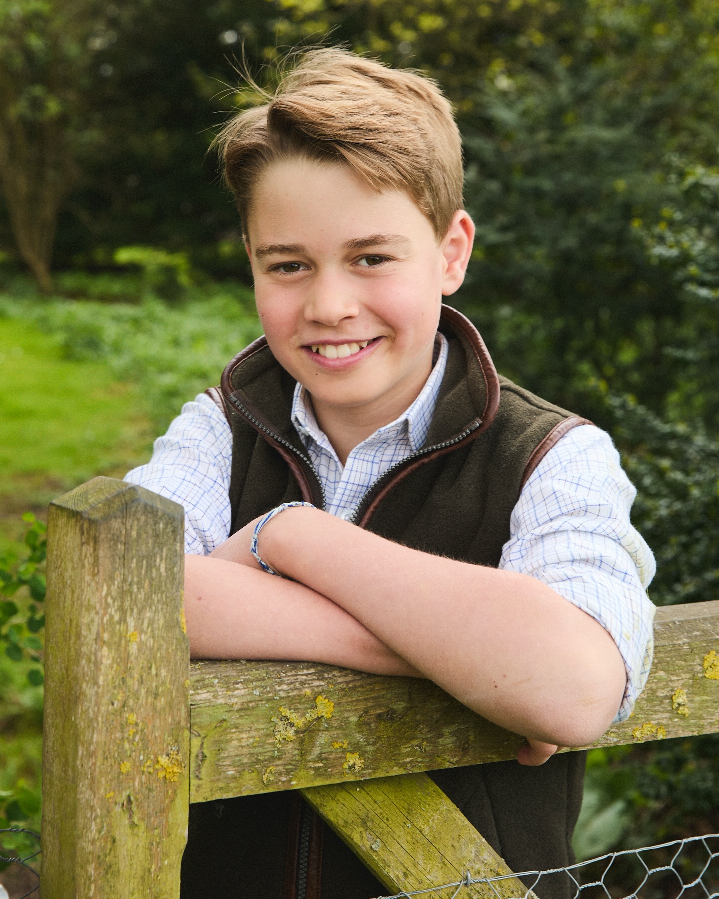 Prince George wearing a vest leaning along a fence in 12th birthday photo