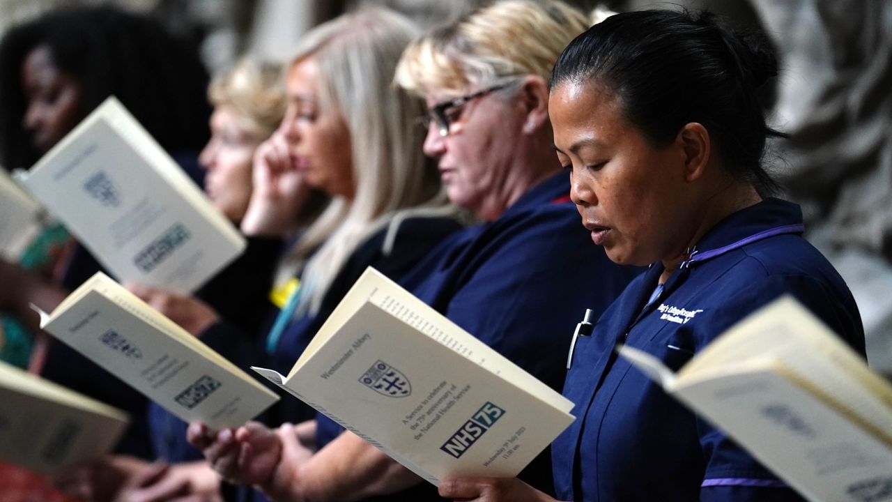 Uniformed NHS staff holding the health service’s anniversary ceremony booklets