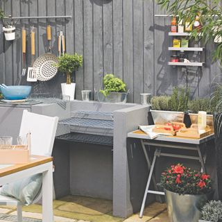 outdoor kitchen with grill based BBQ, hanging storage, tray table, dining table on left