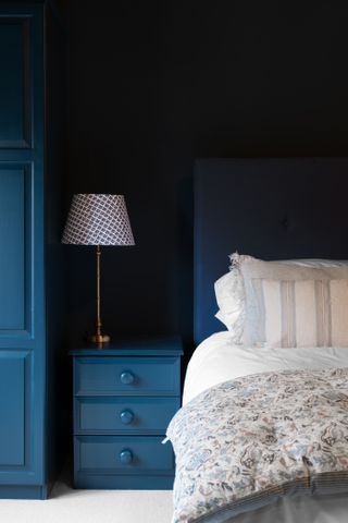 Hague blue bedroom where the nightstand, wardrobe, and head board are all painted in the shade. The bed has white and beige bedding.