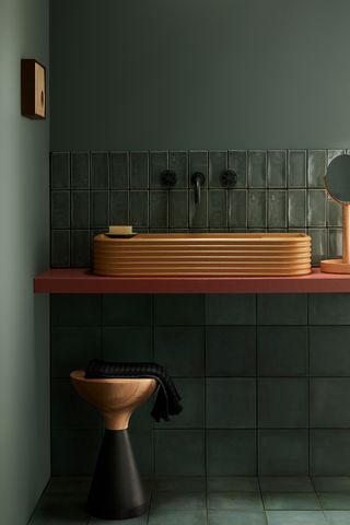Dark green tiled small bathroom with terracotta sink