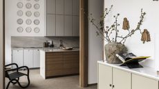 A view into a kitchen with wood effect lower cabinets and grey slab upper units