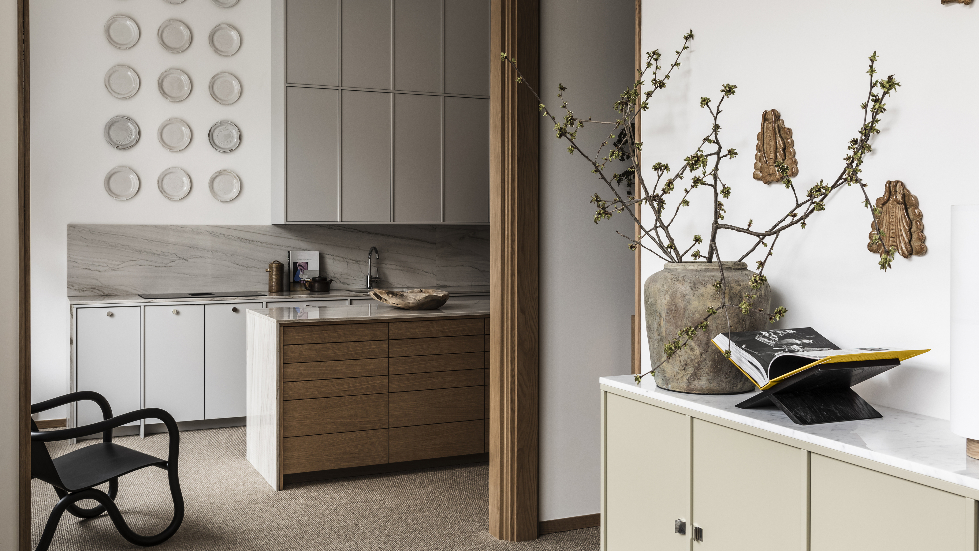 A view into a kitchen with wood effect lower cabinets and grey slab upper units 