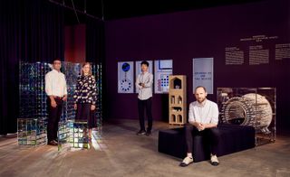 Four people standing amongst the designs submitted to the awards