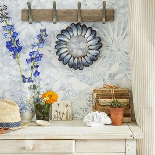 white wooden table with blue designed wall and flower vase