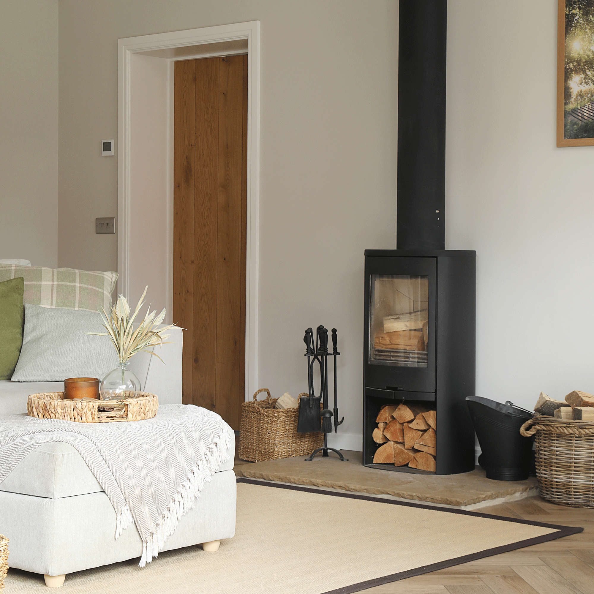 a living room with a logburner, herringbone flooring and a cream sofa