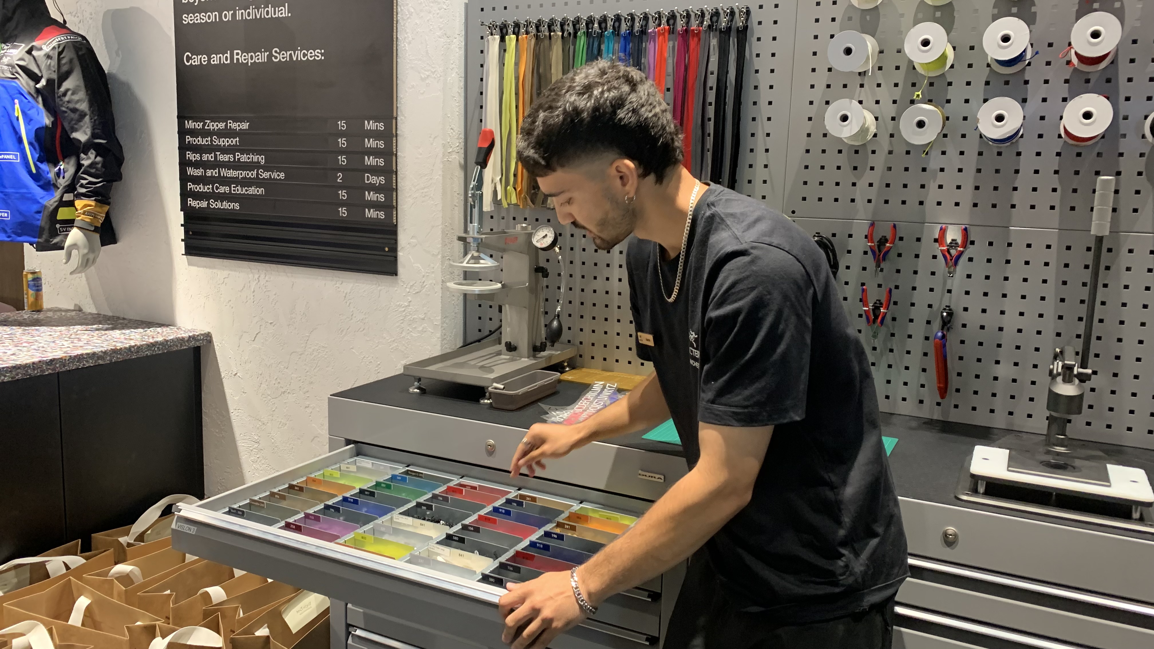 A staff member at the Arc'teryx ReBird service center opens a drawer full of colorful patches