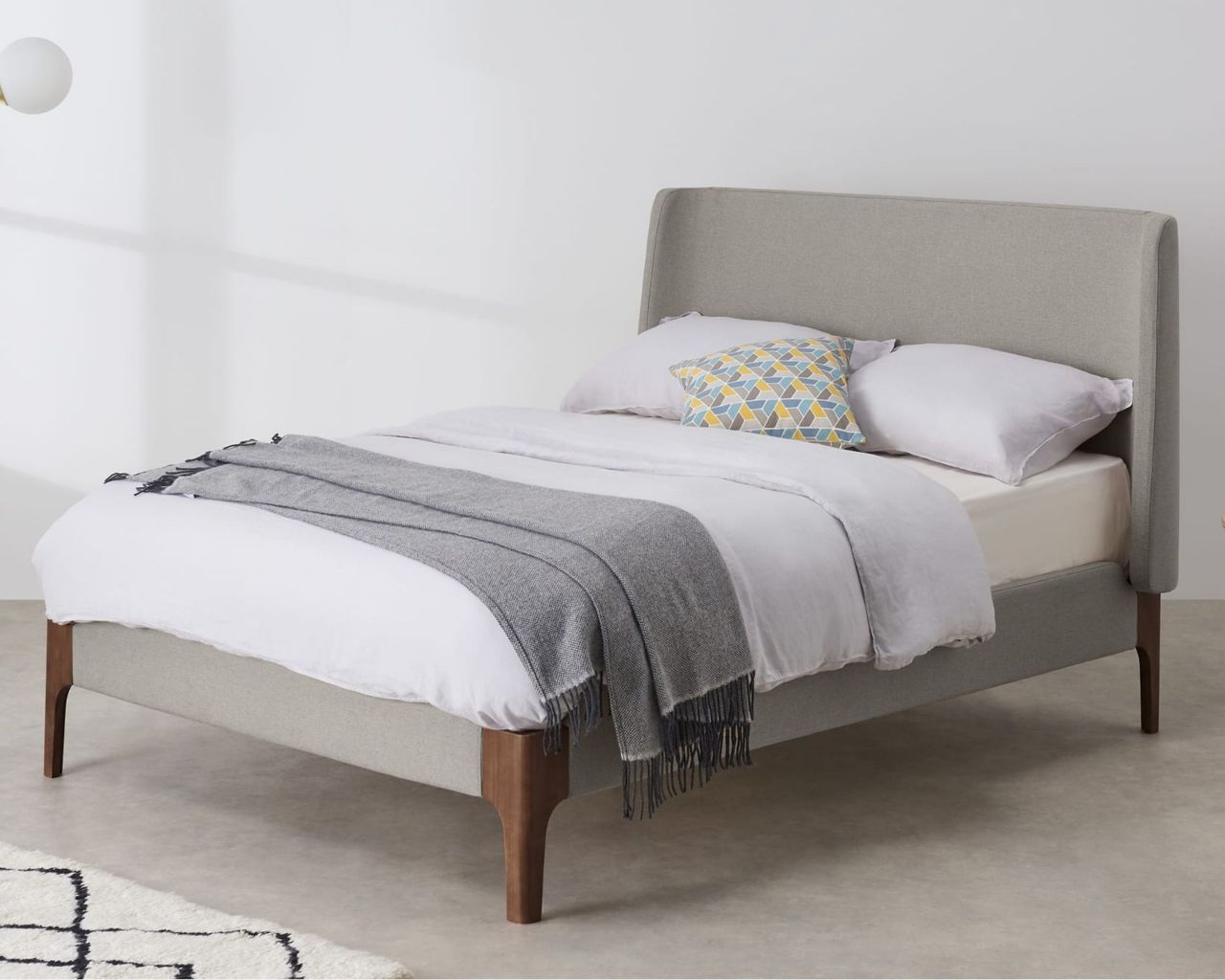 Made Roscoe King Size Bed in beige inside white room with white bedding, grey throw, marble floor lamp and rug
