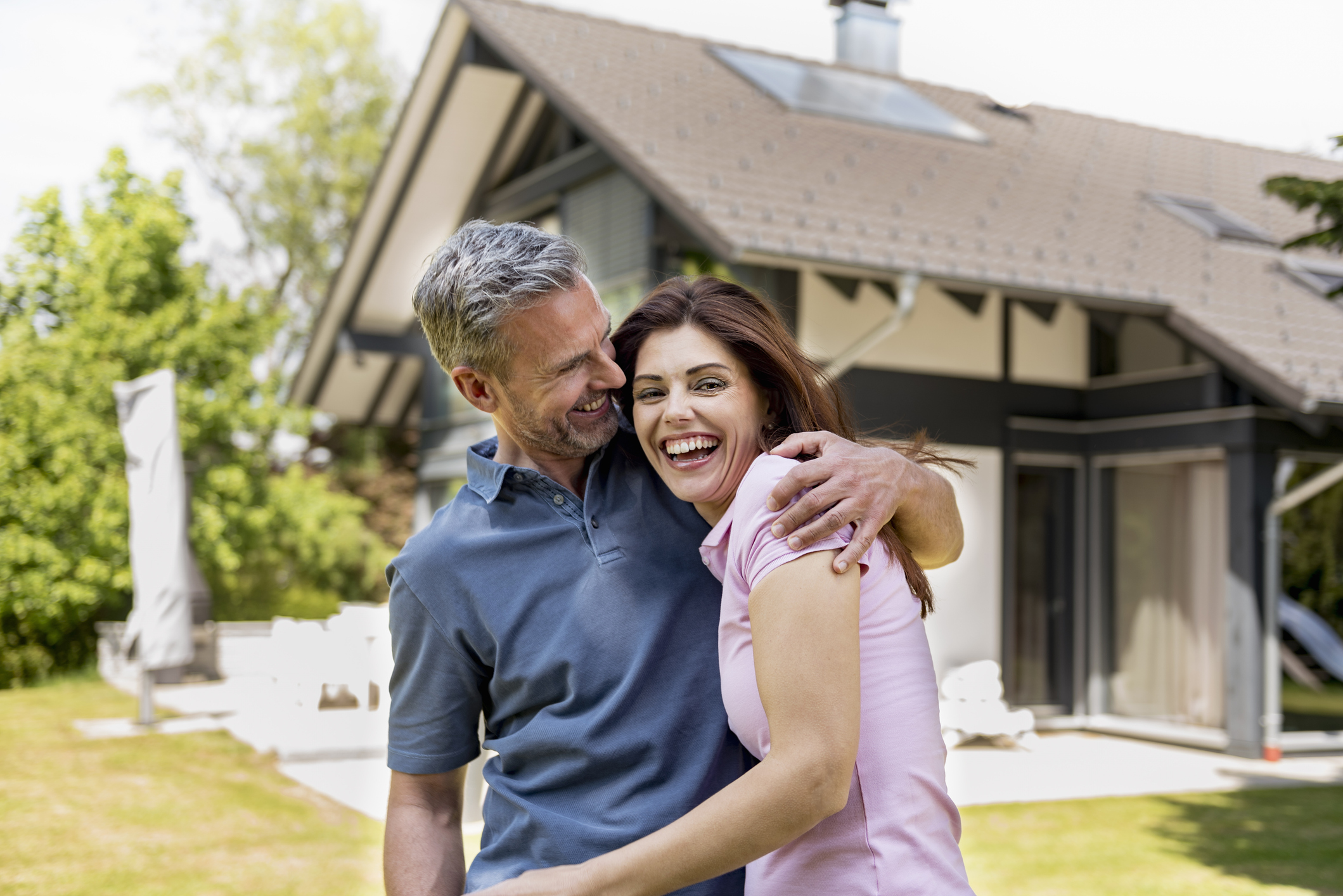 A happy, middle-aged couple in front of their home.