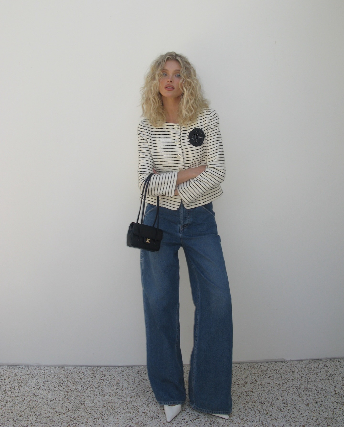 Elsa Hosk poses for a photo wearing a striped cropped jacket with wide-leg jeans and white pointed-toe heels.