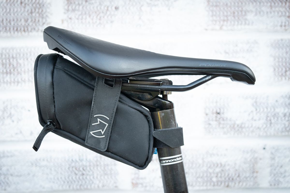 Pro Performance compact saddlebag in black attached to saddle rails and seatpost with velcro straps