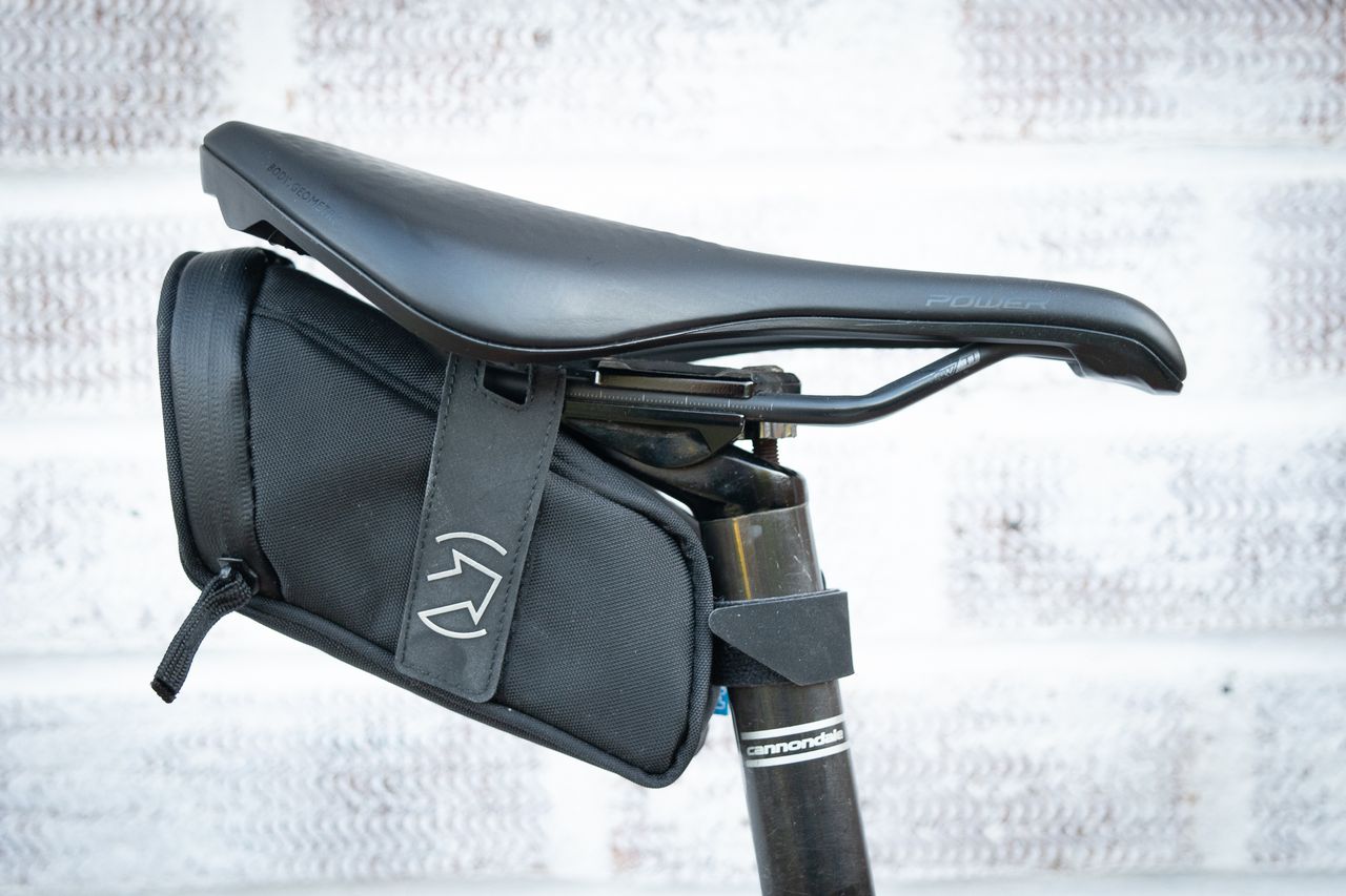 Pro Performance compact saddlebag in black attached to saddle rails and seatpost with velcro straps