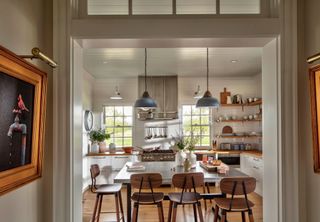guest kitchen with wooden floor and wooden backed chairs and steel cooker hood