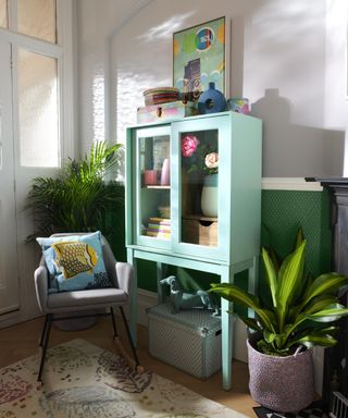 Mint green cabinet in hallway with chair by Homesense