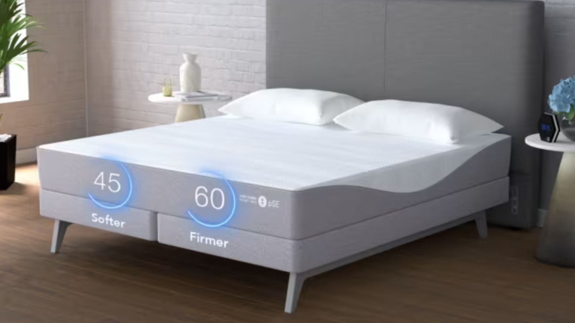 Grey and white Sleep Number on grey bed frame on wooden floor with white brick wall behind bed
