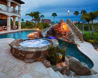 pool with slide, hot tub, and lights