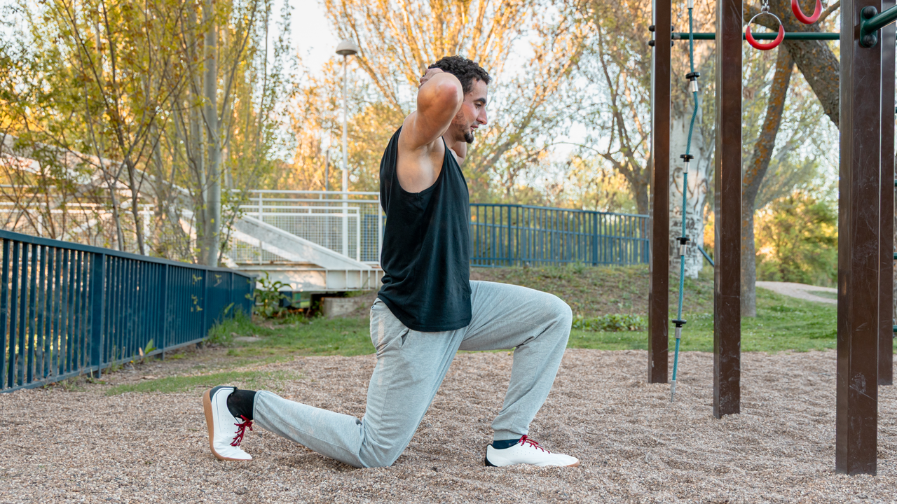 A man performing reverse lunges outside