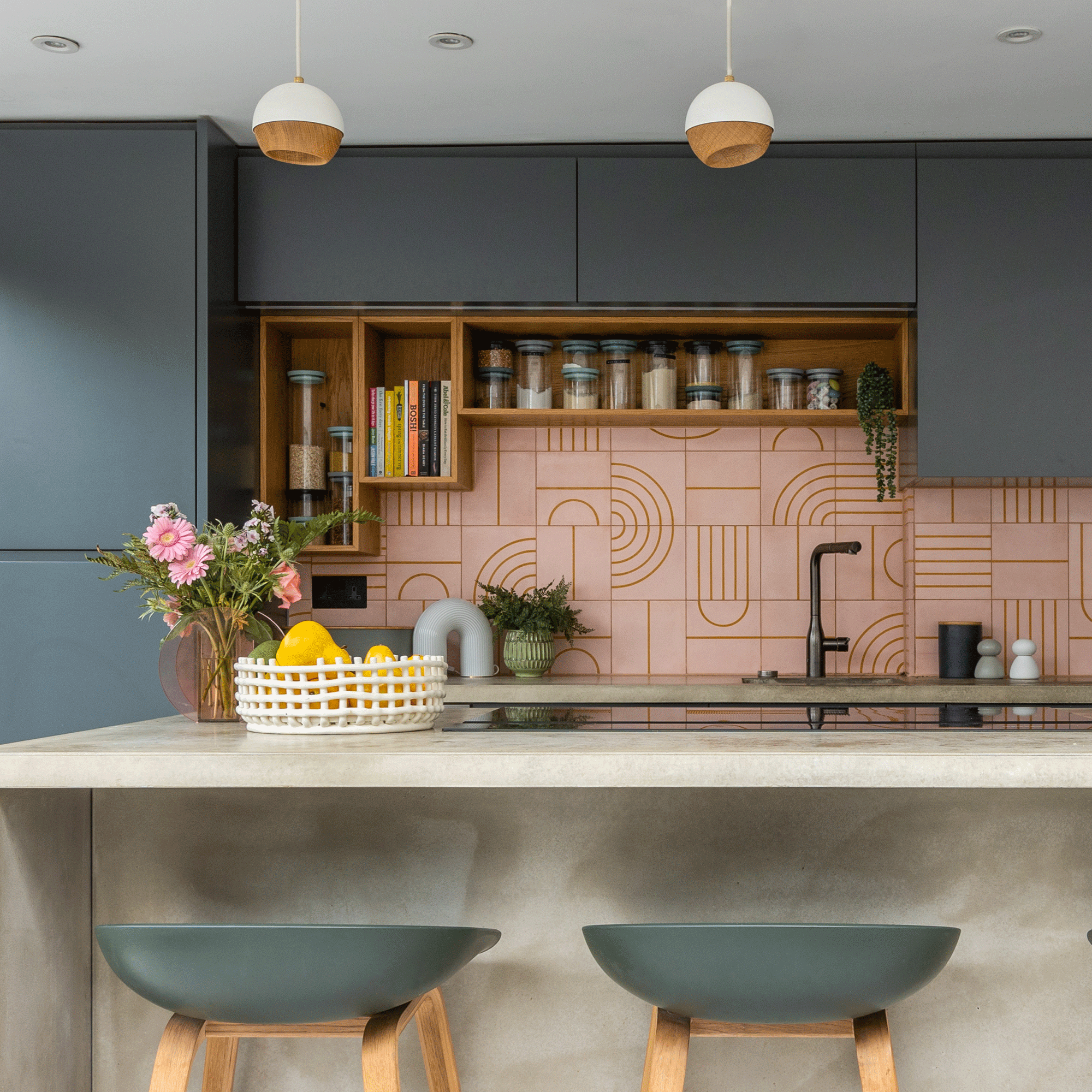 Blue kitchen cabinets with pink tiles and a micro cement kitchen island