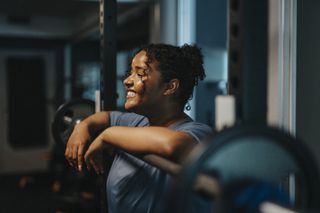 A smiling woman in the gym lifting weights.