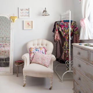 white bedroom with pink armchair and clothes hanger