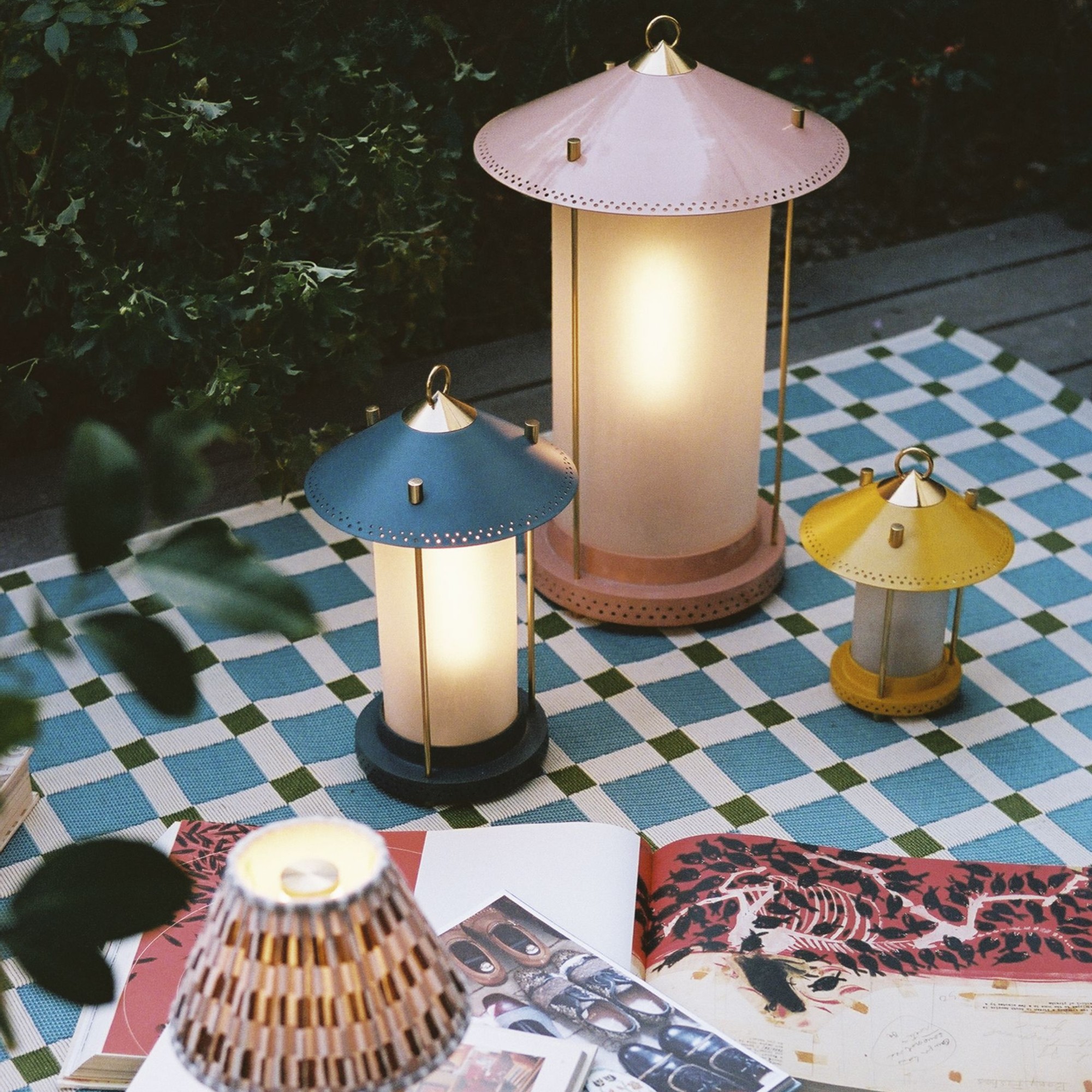 The Pooky Stefan rechargeable lanterns by The Novogratz in all three sizes on a checked blanket with open magazines next to them