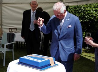 Britain's Prince Charles, Prince of Wales, prepares to cut a cake during his visit to the Coventry Church Municipal Charities Bond's Hospital in Coventry, central England on May 25, 2021, to celebrate the Association's 75th anniversary.
