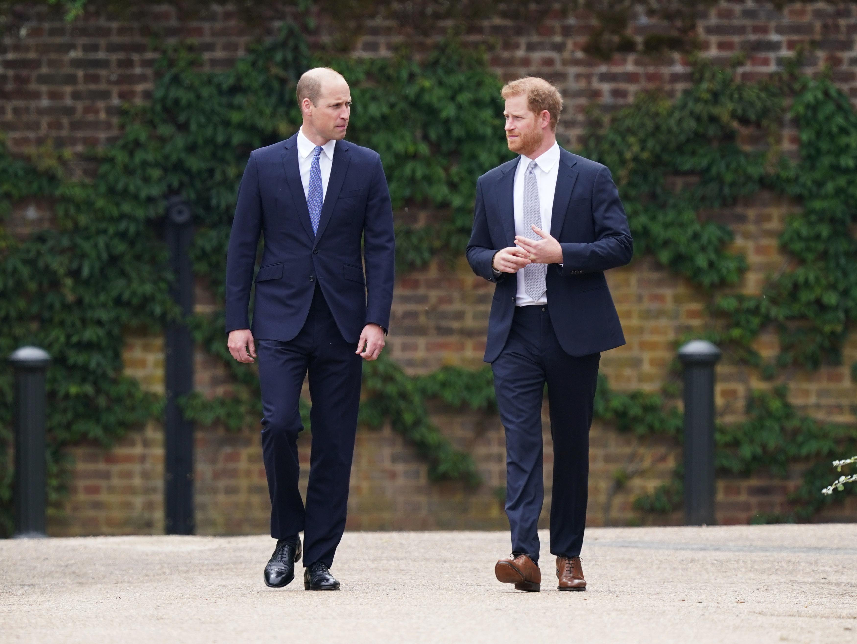 Prince William and Prince Harry both wearing suits, white shirts, and ties