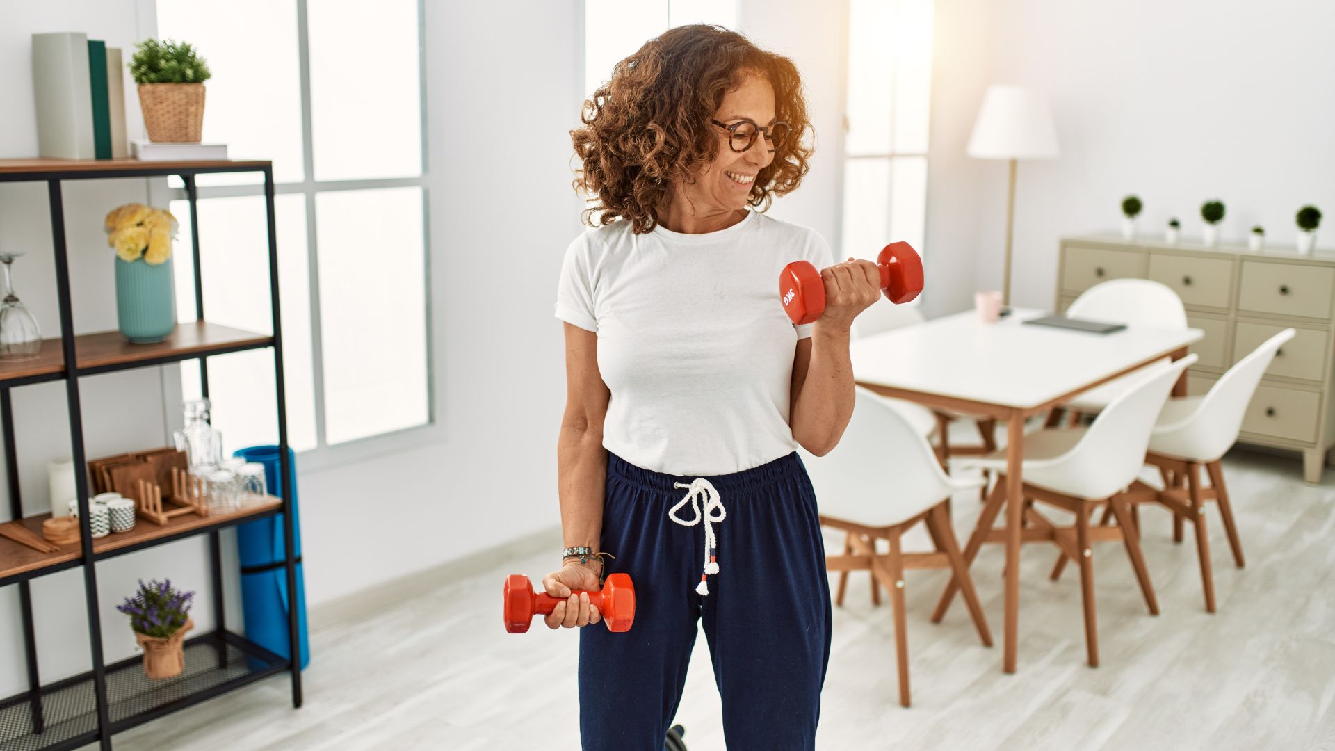 Woman doing dumbbell workout at home in kitchen, smiling