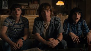 Finn Wolfhard Charlie Heaton and Noah Schnapp sitting on a couch in Stranger Things