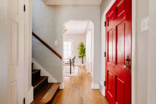 Red entryway door in painted white brick hallway with wooden floors