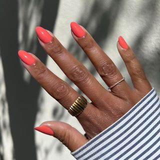 A woman's hand with coral nail polish.