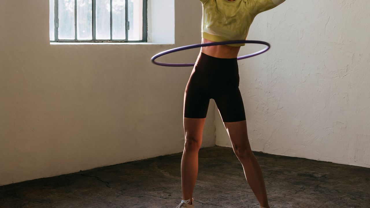 woman using an exercise hula hoop in an empty room