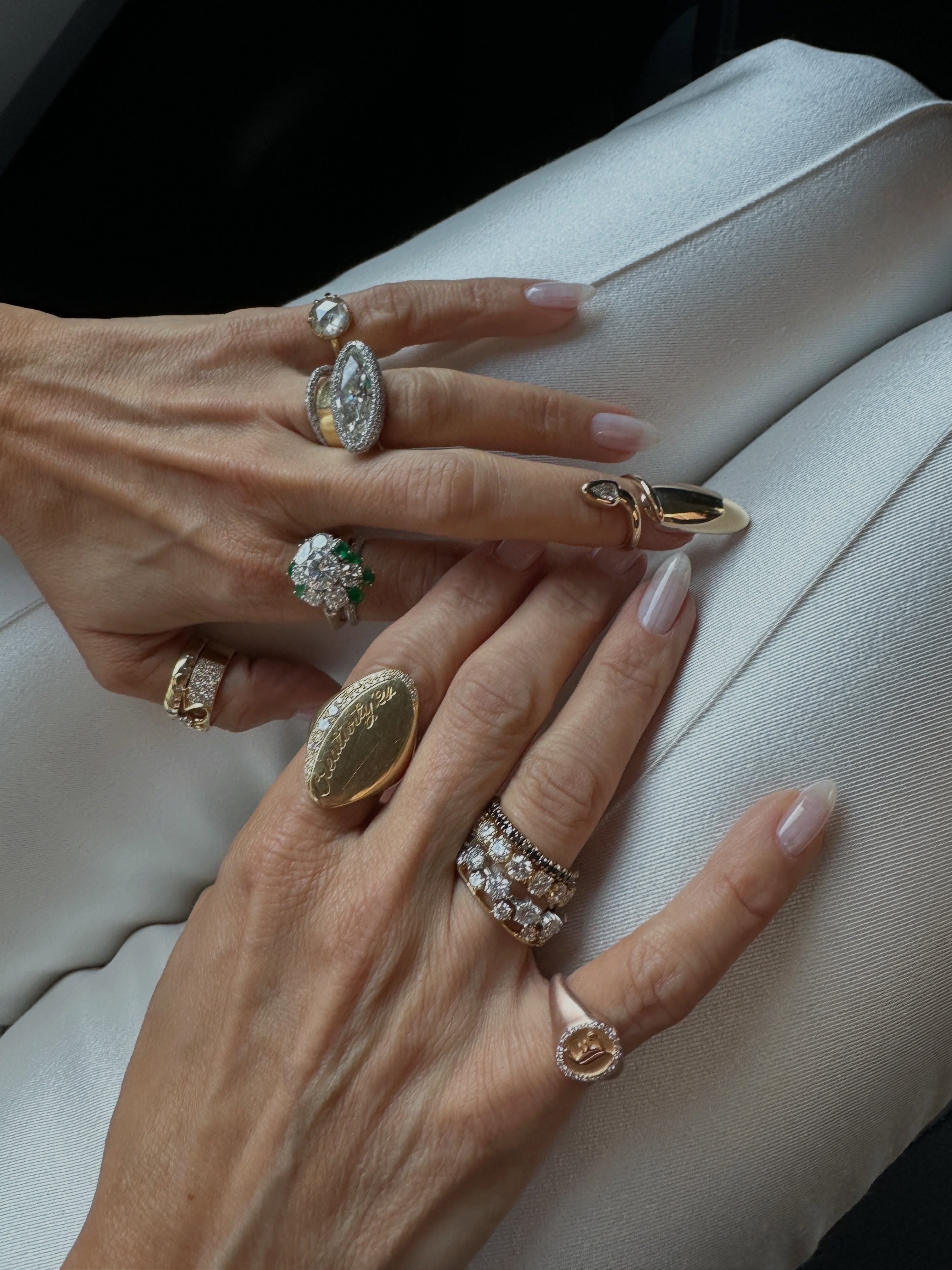 Clean, barely-there manicure surrounded by stacked gold rings and finished with a sculptural nail ring