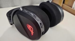 The Asus ROG Pelta gaming headset lying on a table with a glowing red logo