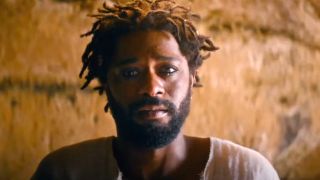 LaKeith Stanfield crying while sitting in front of a torch in The Book of Clarence.