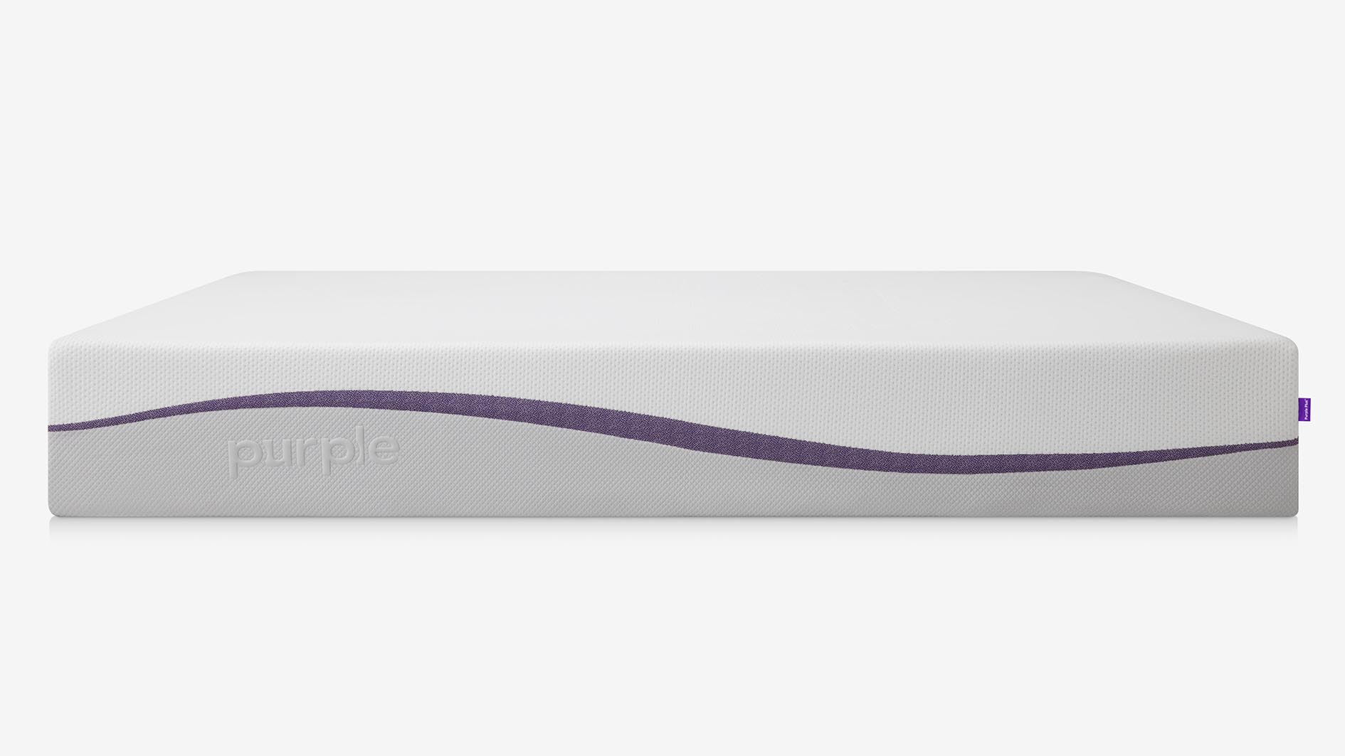 Purple Plus Mattress review: The mattress shown from the side with a light gray base, white top and purple curved stripe down the middle