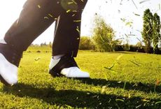 A man in Golf Shoes tees off on a green