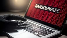 Male hacker hand on laptop computer keyboard with red binary screen of ransomware attack