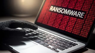 Male hacker hand on laptop computer keyboard with red binary screen of ransomware attack