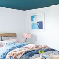 A bedroom with white walls and a blue ceiling, with pink and blue accents