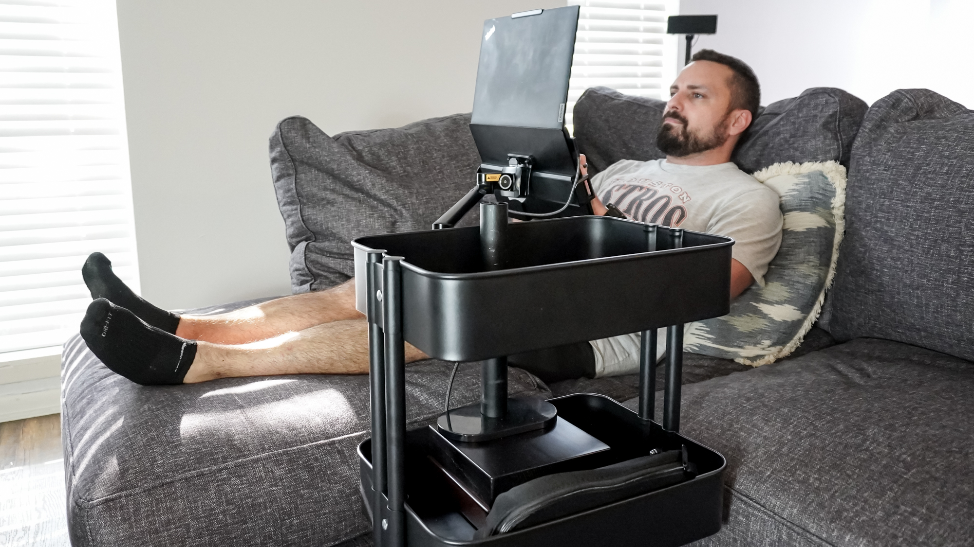 A person working on a laptop at a DIY rollable workstation from the couch