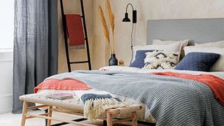 Japandi bedroom scheme with ladder towel and bed with coral and blue accent colors