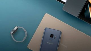 A Samsung watch, laptop and phone on a blue background