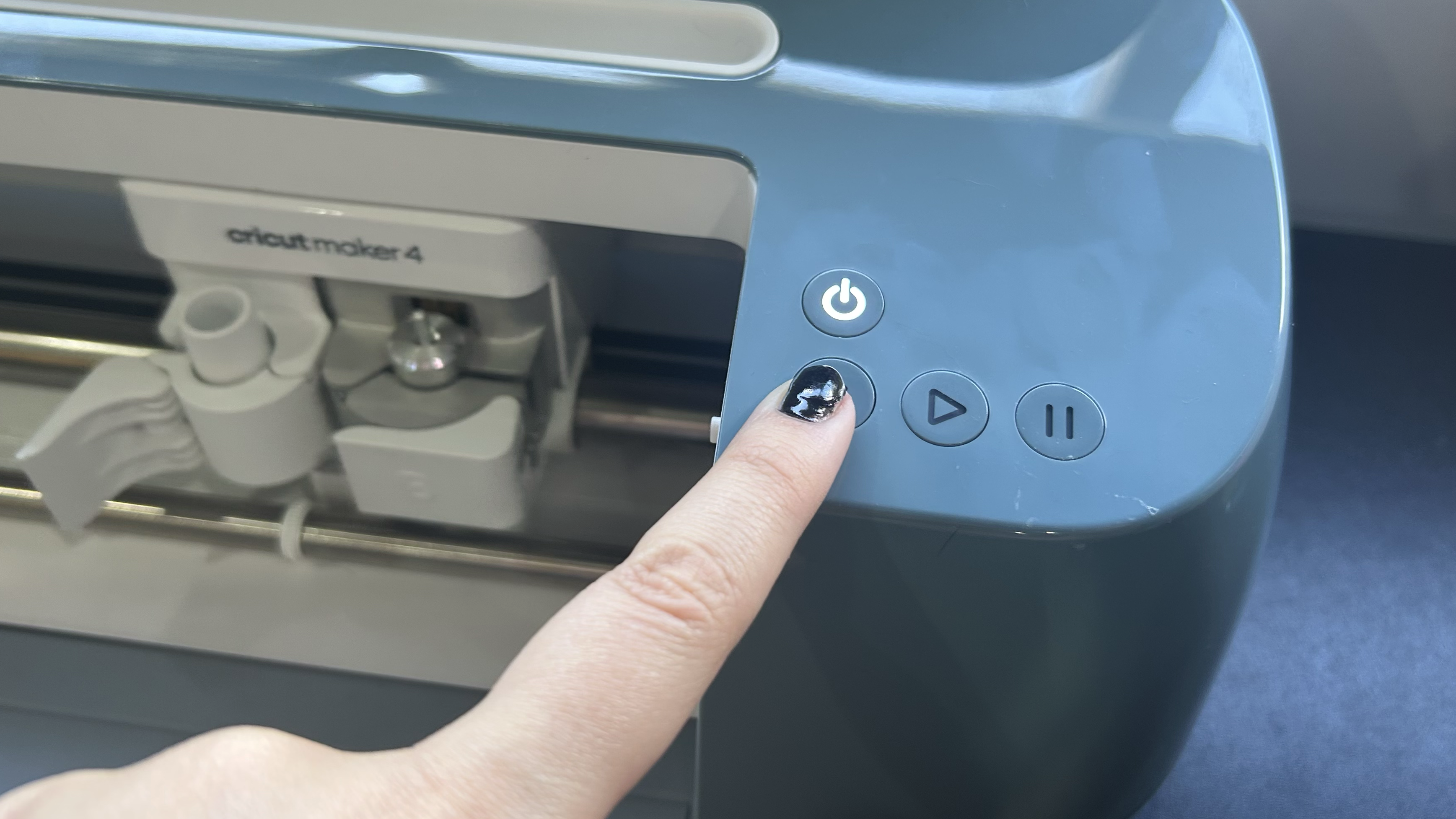 Finger pressing Cricut Maker 4 button