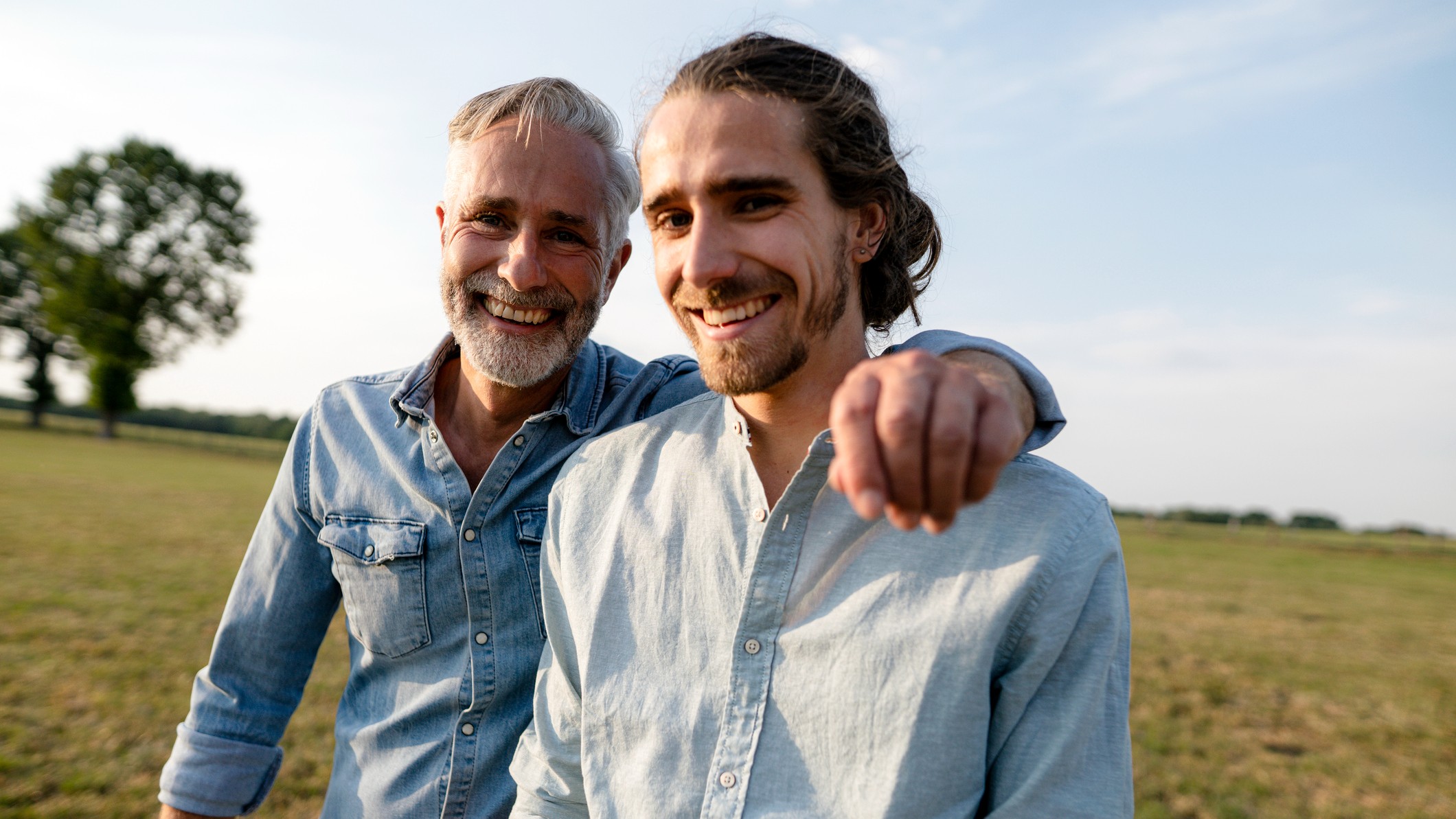 Portrait of a happy father with an adult son in a meadow in the countryside.