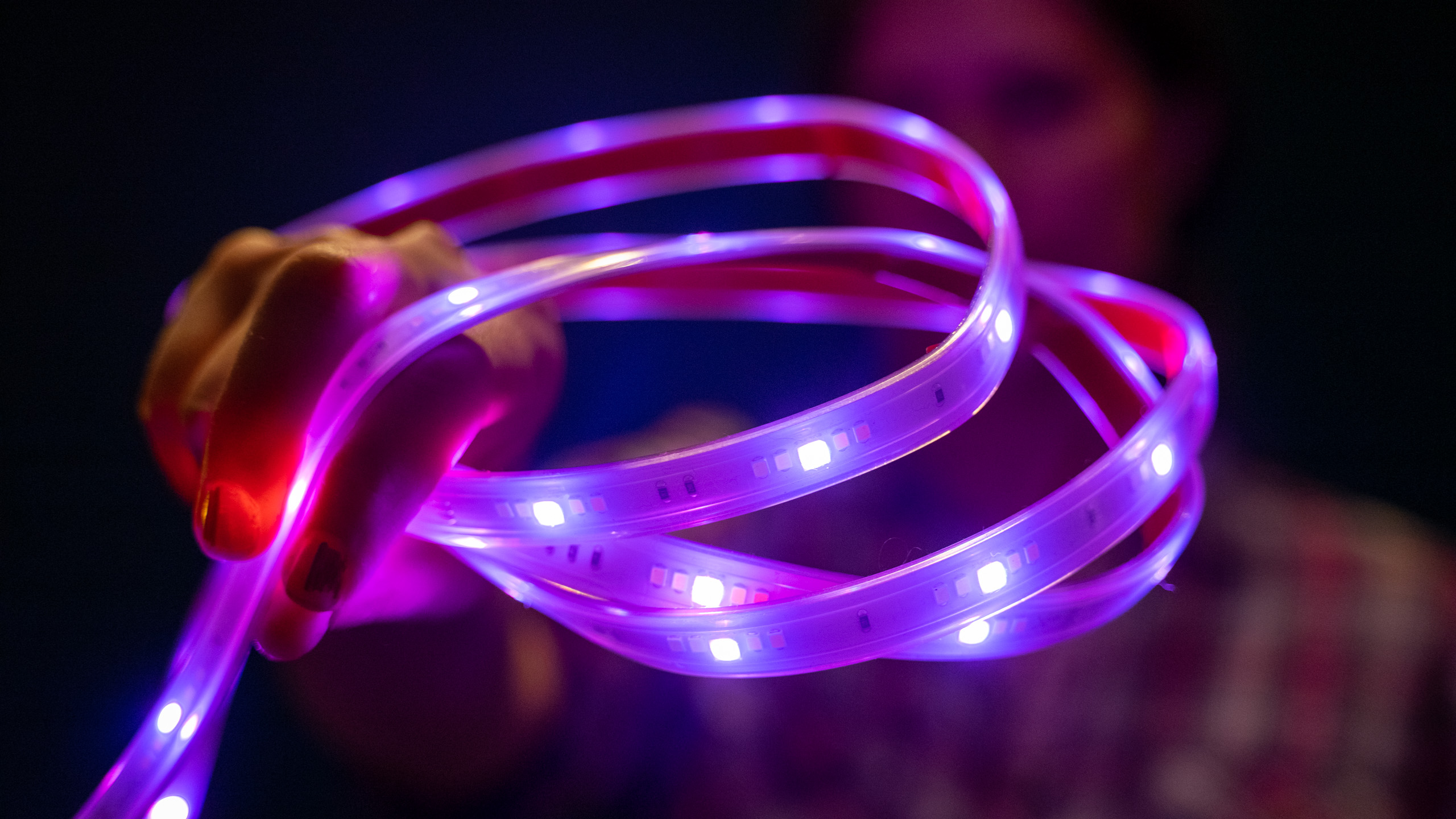 Person håller Nanoleaf Essentials Lightstrip hoprullad i handen framför ansiktet.